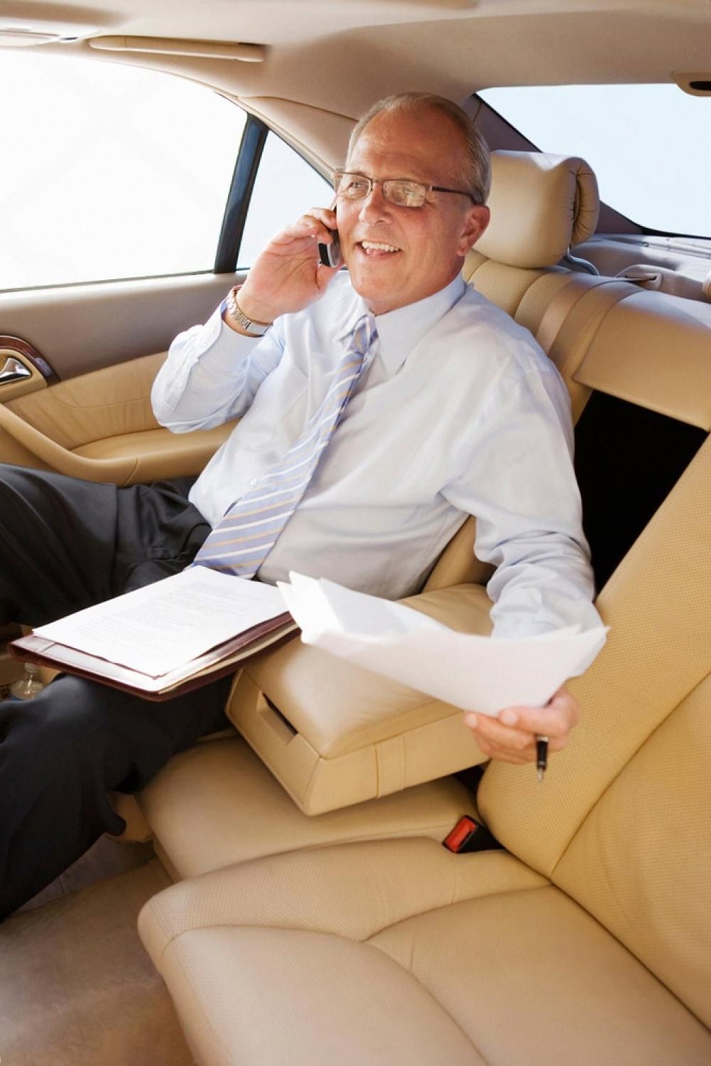 Business passenger on a phone call in the back seat of a chauffeur-driven car in the UAE